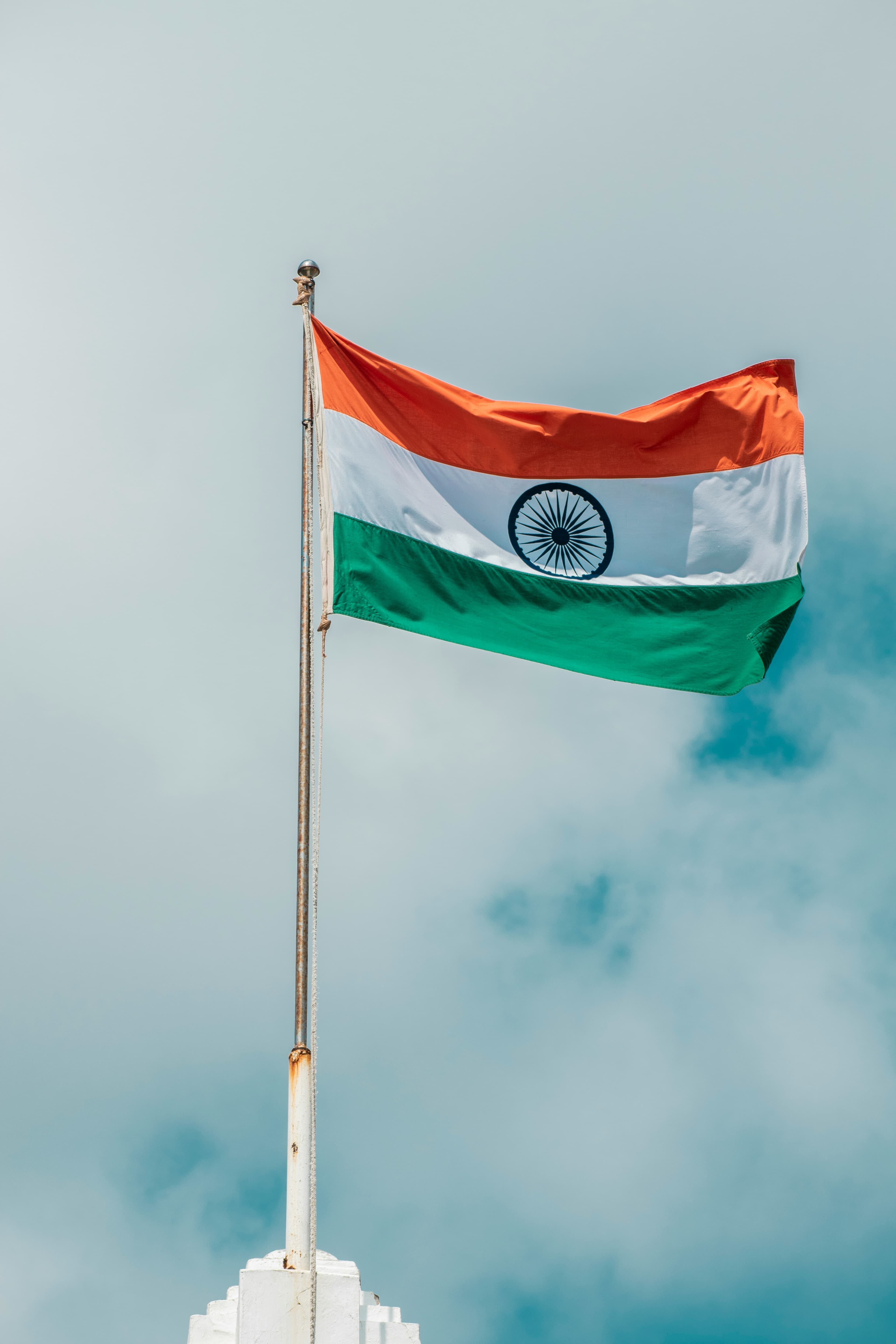 Indian tricolour flag flying against a clear sky.